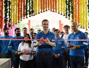 Guillaume Dourdin coupant le ruban inaugural rouge entouré des équipes Veolia sous une arche de guirlandes de fleurs traditionnelles.