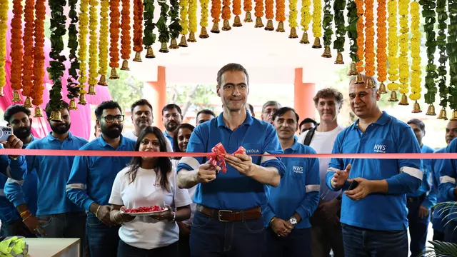 Guillaume Dourdin coupant le ruban inaugural rouge entouré des équipes Veolia sous une arche de guirlandes de fleurs traditionnelles.